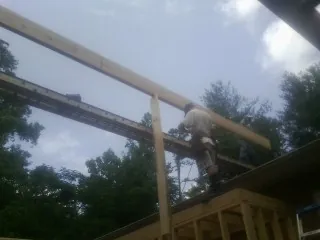Carpenter setting a ridge beam over a new addition frame — Ice Dam Removal by Roofing Brothers in Jourdanton