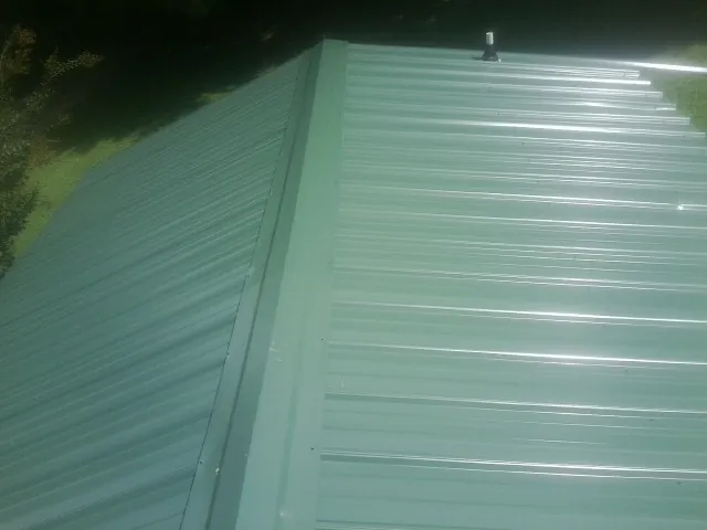 New green metal panels meeting at the ridge of a roof — Flat Roof Repair work by our crew in Jourdanton
