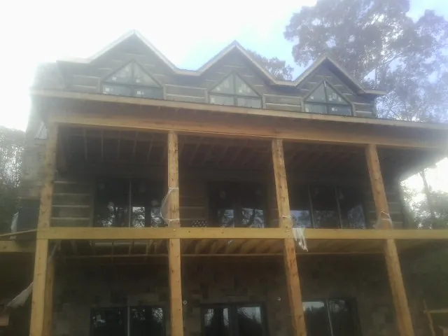 Dormers and porch framing on a large log home under construction — Roof Coating work by our crew in Jourdanton