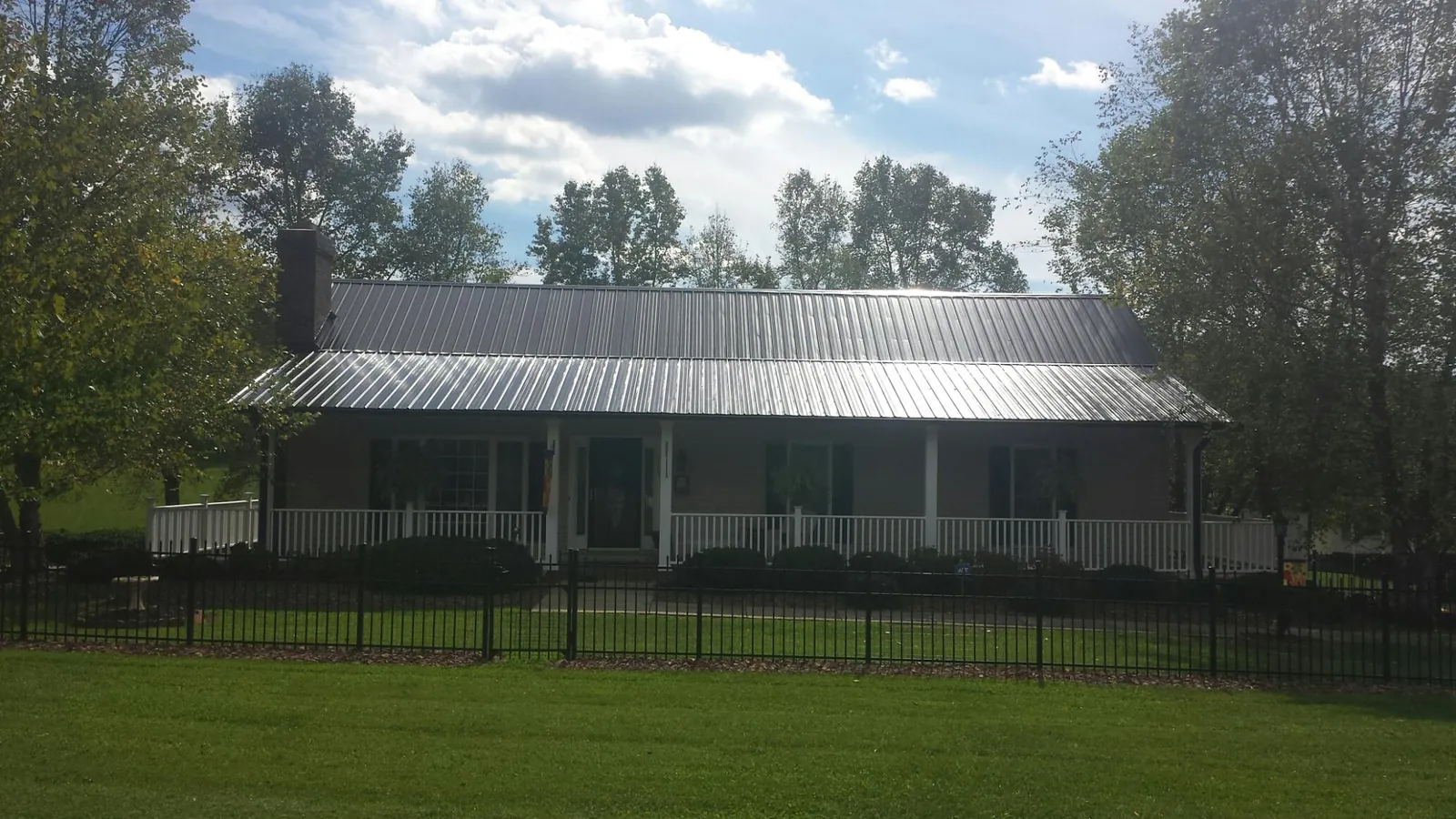 Gray metal roof on a brick ranch with a full width front porch — Gutter Guard Installation work by our crew in Jourdanton