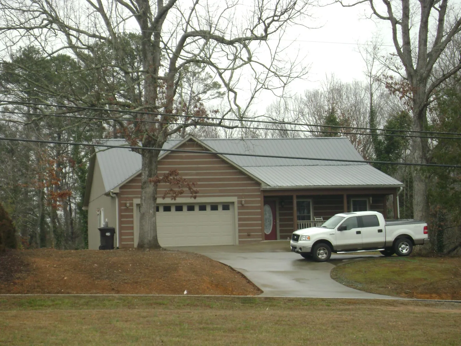 Gray metal roof on a log sided house with an attached two car garage in Jourdanton