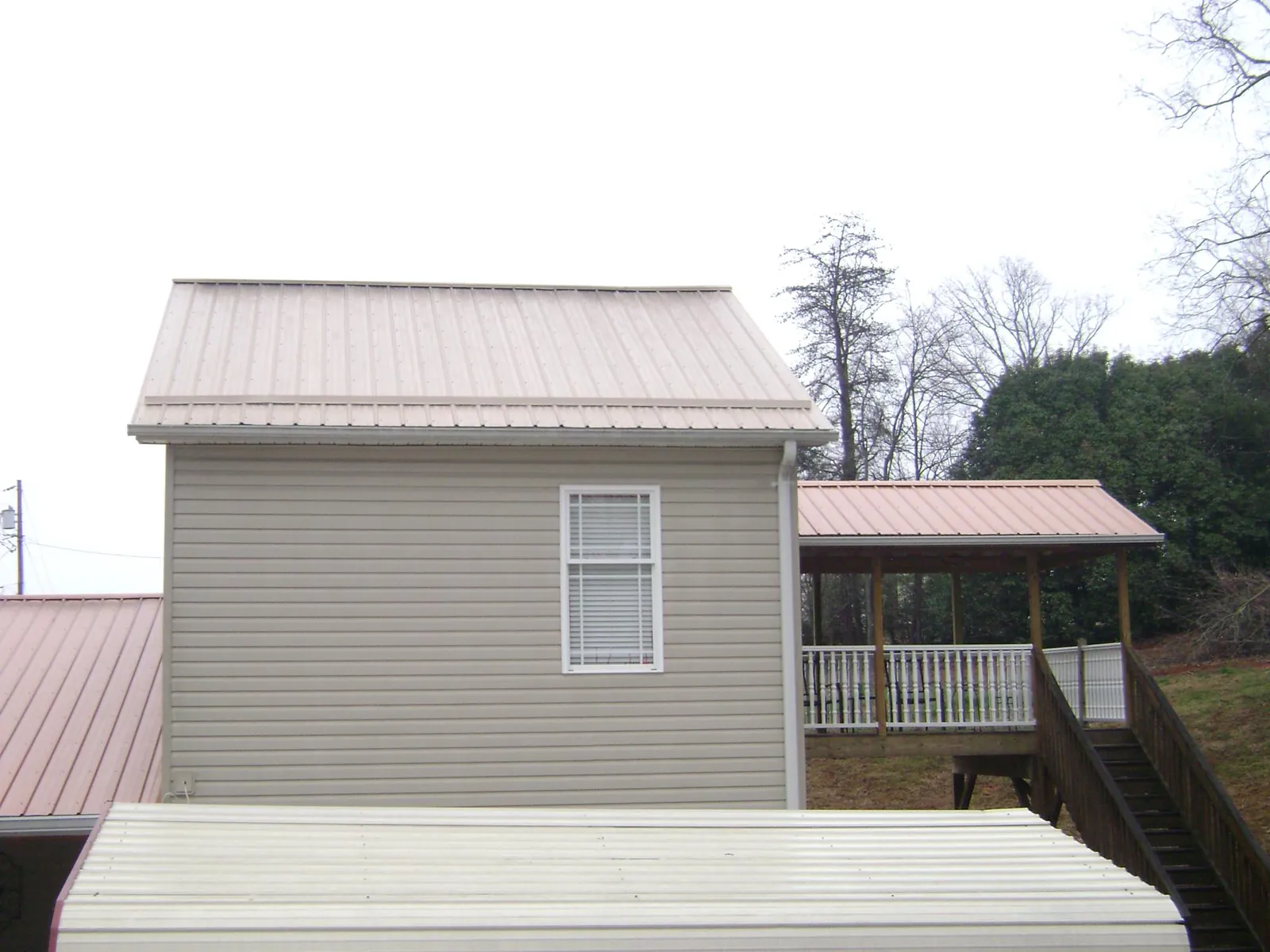 Tan metal roofs on a two story addition and attached porch, from a Roof Replacement job in Jourdanton